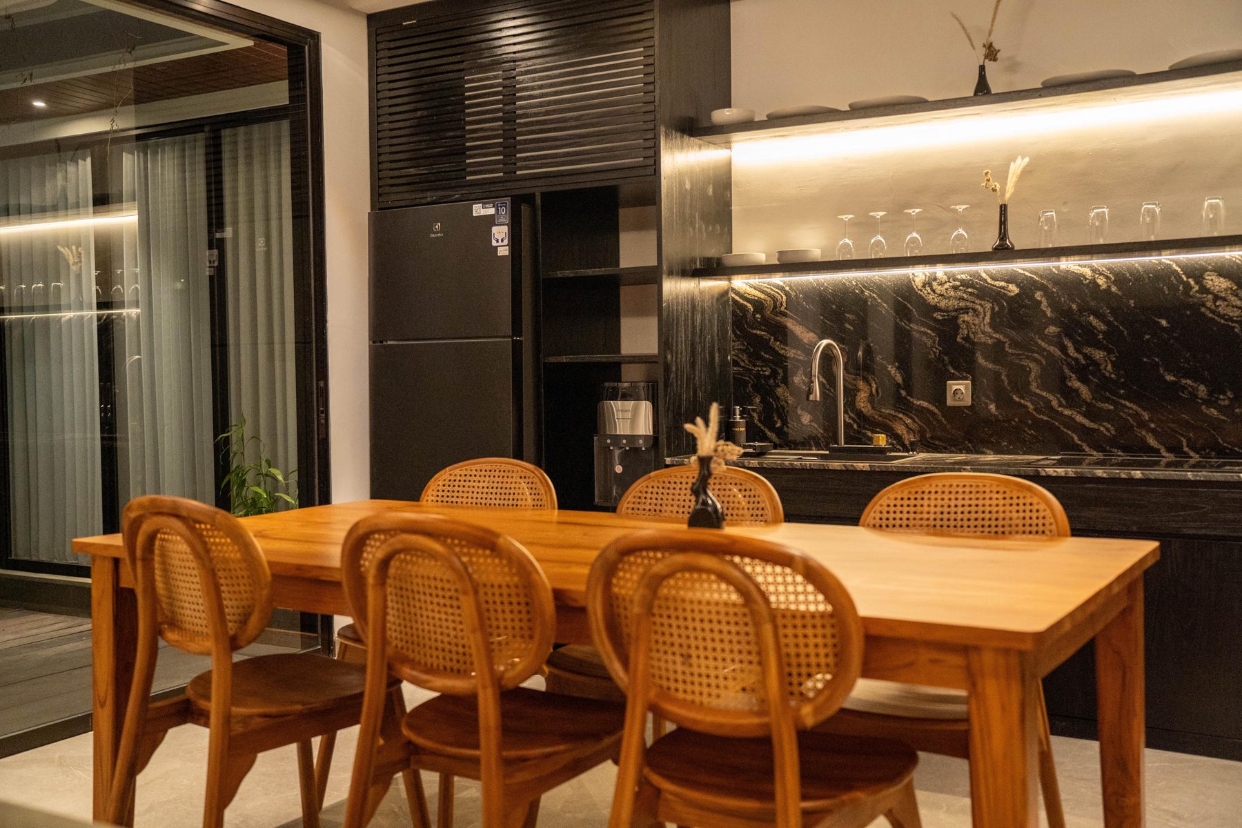 Dining and living area seen from the pool deck at night